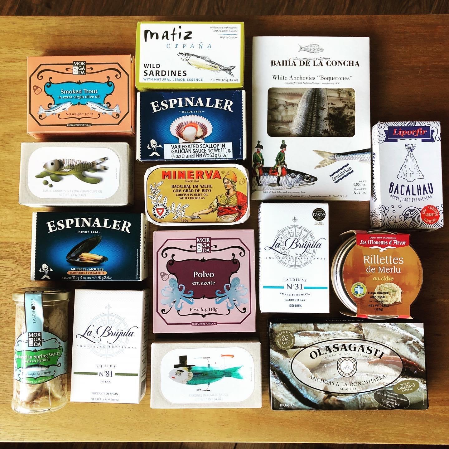 image of approximately 15 tins of fish, such as sardines, trout, etc. on a table arranged in grid