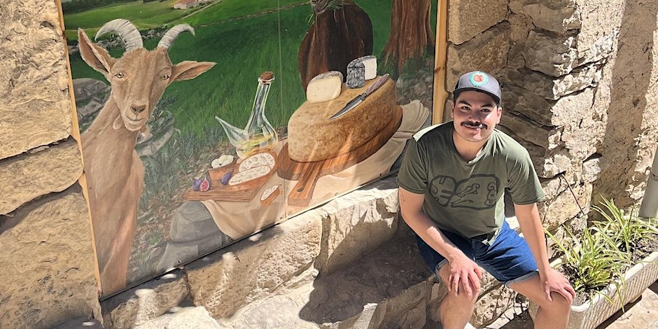 Cheesemonger Jacobe sits next to a painted scene of cheese and wine and Saint Gil d'Albio dairy in Spain